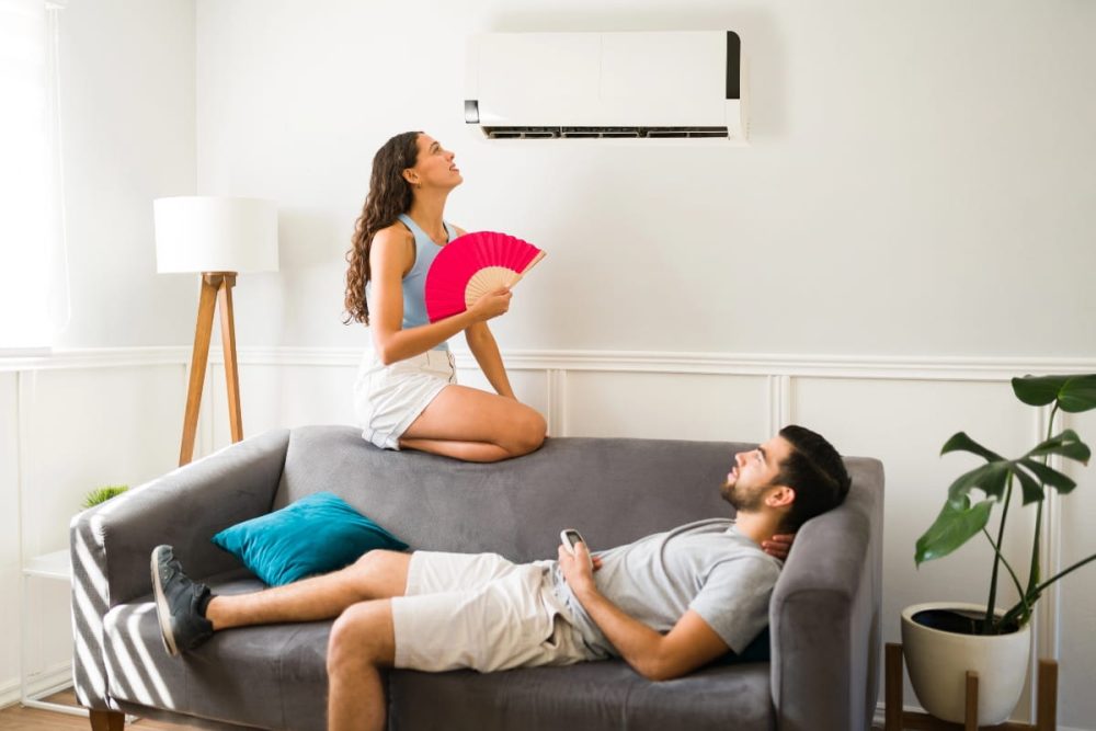 Tenants cooling down in a rental home with an air conditioner needing maintenance.