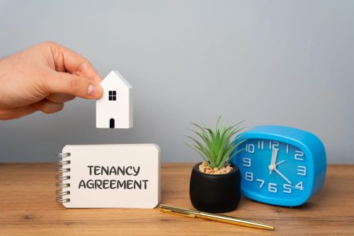 Clock, plant, and a tenancy agreement notebook, with a house model highlighting the topic of can a landlord break a lease?