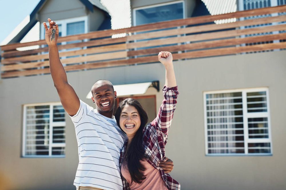 Happy homeowners embracing and cheering after successfully purchasing their new house.