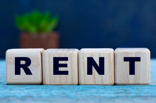 Wooden blocks spelling out the word 'RENT' on a blue background, representing signs your rental application will be approved.