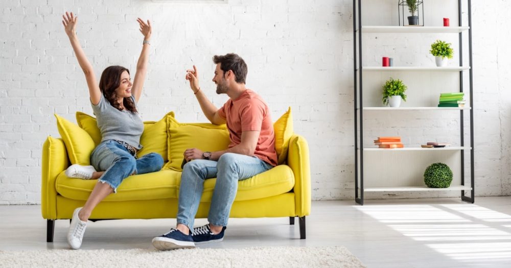 Couple on yellow sofa excited to be new rental property tenants.