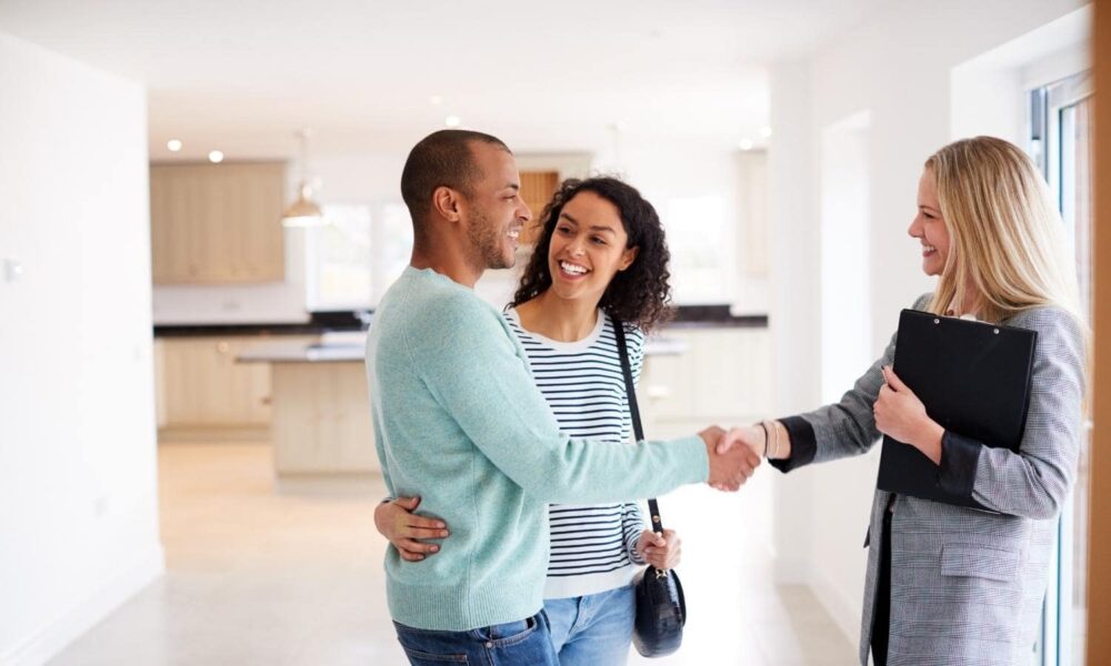 Couple handshaking a real estate agent.