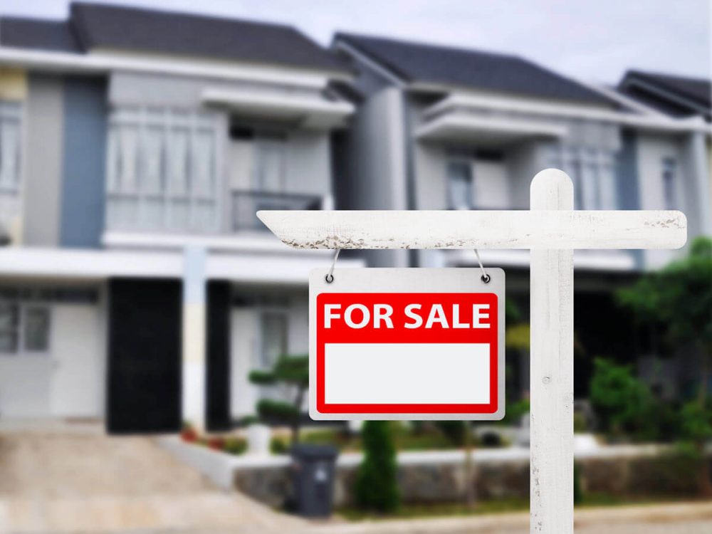 A property for sale sign positioned in front of a modern suburban home, ready for potential buyers.