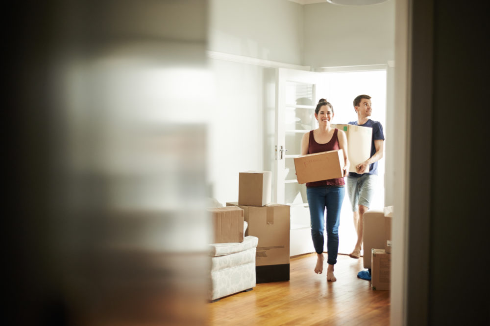 Shot of a young couple carrying boxes into their new place.