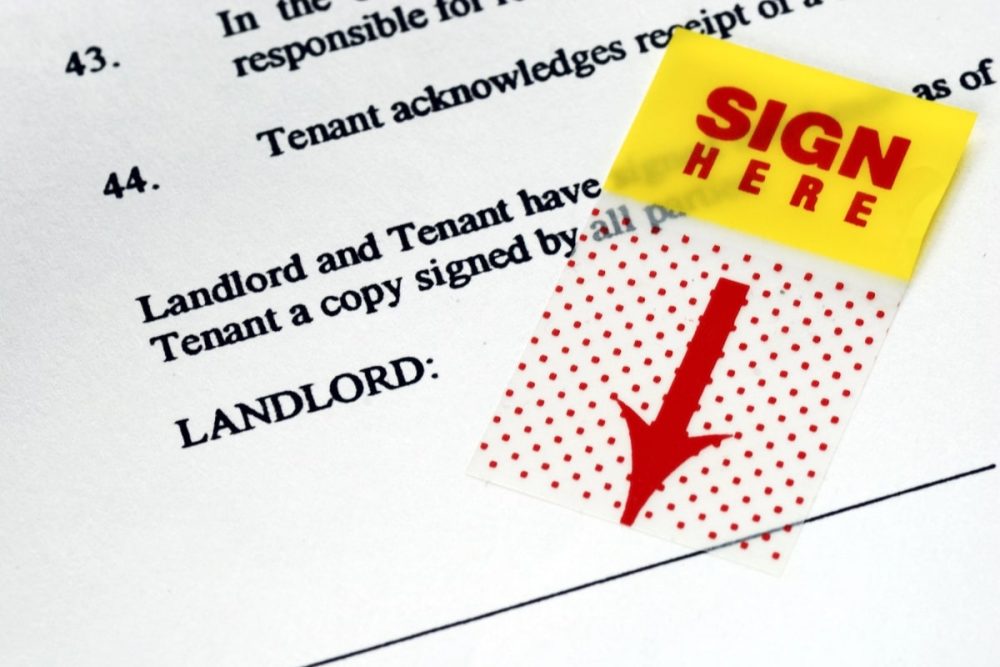 Highlighted section of a tenancy agreement with a clear 'Sign Here' tab, representing approval stages in rental applications.