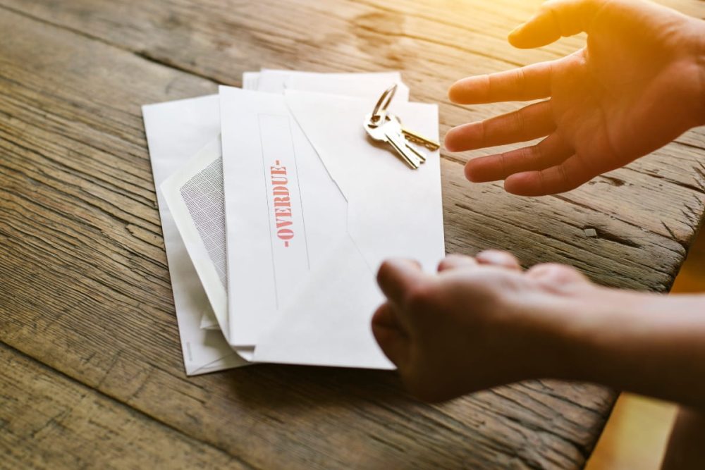 A hand reaching for an overdue letter, representing the consequences of missed payments in rental agreements.