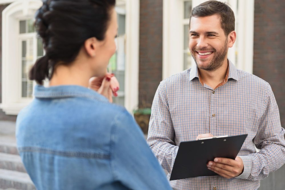 A property manager discussing responsibilities with a landlord outside a residential building.