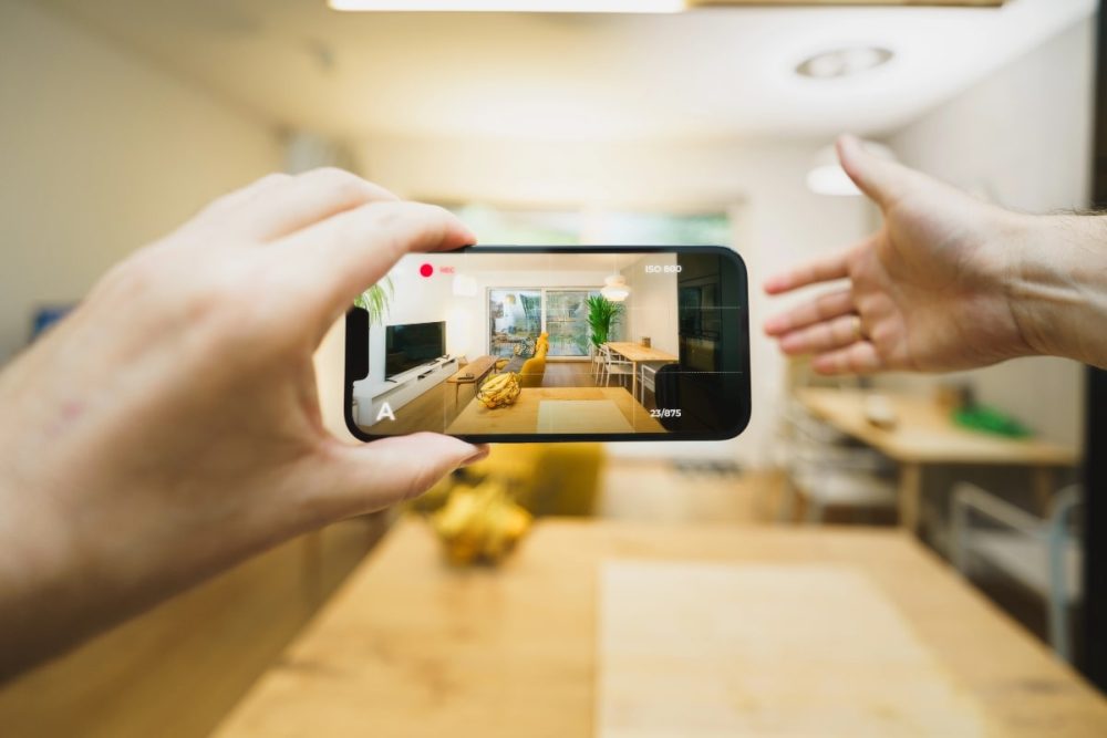 Hands framing a smartphone screen while filming a home interior for a property listing. 