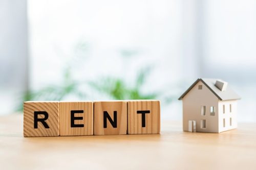 Wooden blocks spelling 'RENT' with a model house.