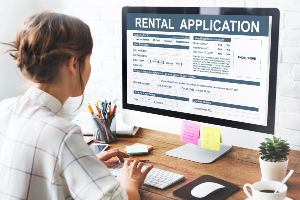 Woman working on a rental application form displayed on a desktop computer, representing the application process.