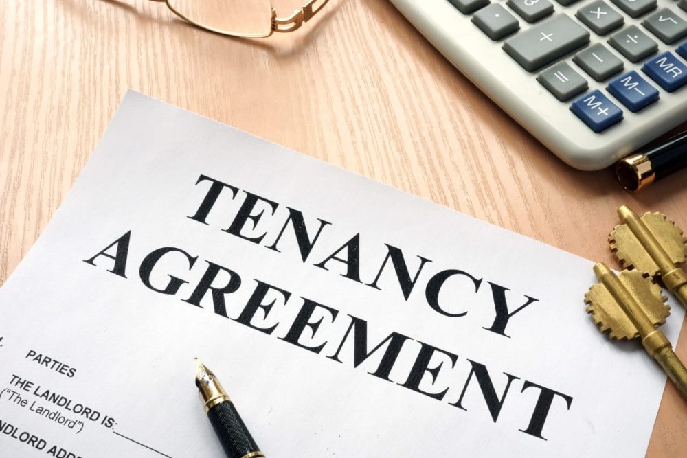Tenancy agreement document on a desk with a calculator and keys.